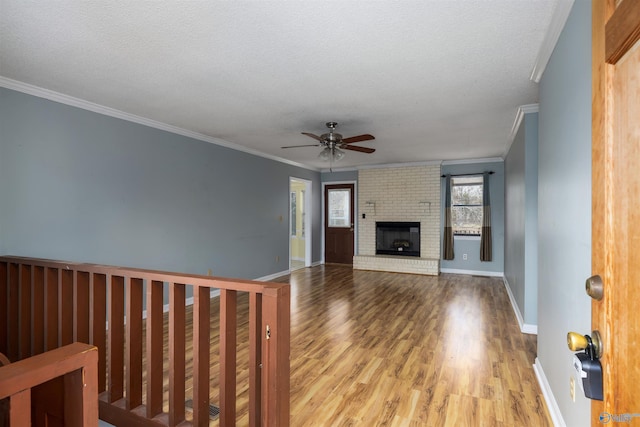 unfurnished living room featuring light hardwood / wood-style flooring, crown molding, a textured ceiling, and a fireplace