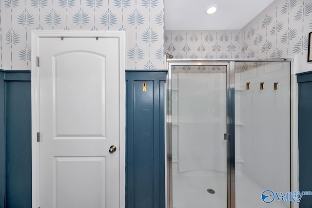 bathroom with a shower stall and wallpapered walls