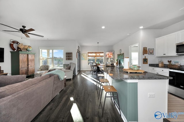 kitchen featuring a breakfast bar, appliances with stainless steel finishes, open floor plan, and white cabinets