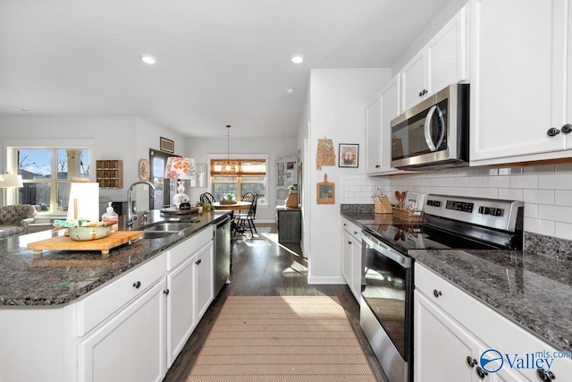 kitchen featuring dark wood finished floors, stainless steel appliances, backsplash, white cabinets, and a sink