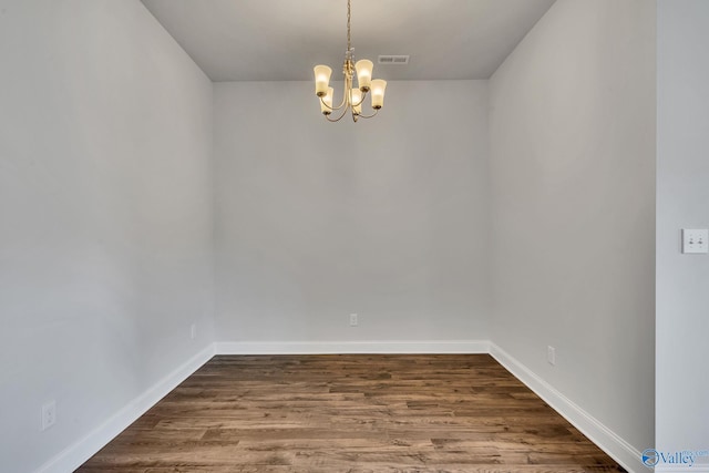 unfurnished room with dark wood-style floors, a chandelier, visible vents, and baseboards