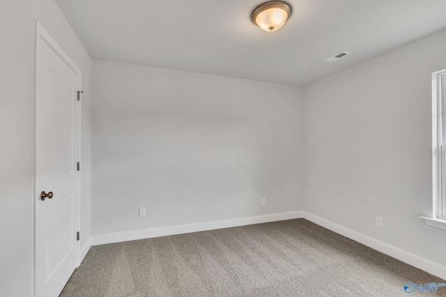 carpeted spare room with visible vents and baseboards