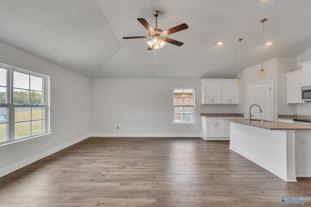 kitchen featuring white cabinets, hanging light fixtures, dark stone countertops, and stainless steel microwave