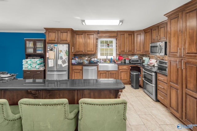 kitchen featuring a kitchen breakfast bar, stainless steel appliances, backsplash, sink, and light tile patterned floors