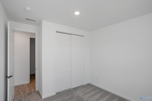 unfurnished bedroom featuring light colored carpet and a closet