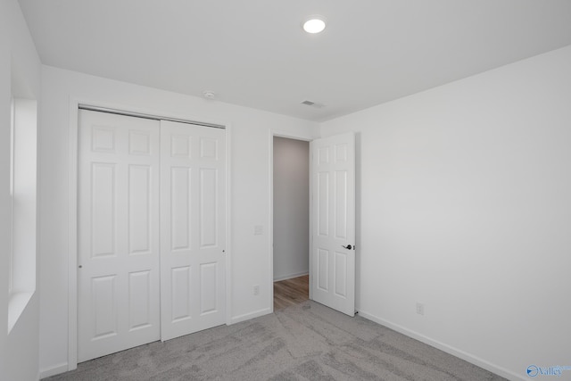 unfurnished bedroom featuring light colored carpet and a closet