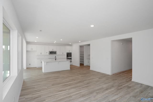 unfurnished living room with sink and light hardwood / wood-style floors