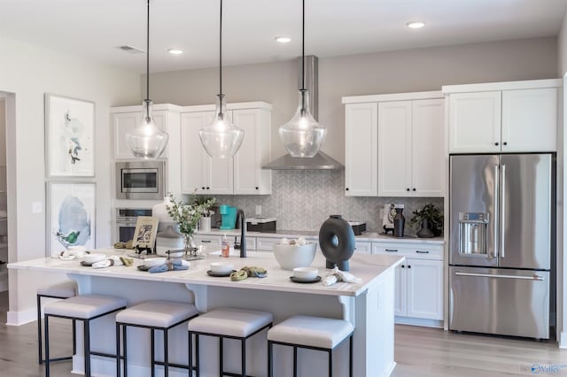 kitchen featuring stainless steel appliances, a kitchen island with sink, white cabinets, and a breakfast bar