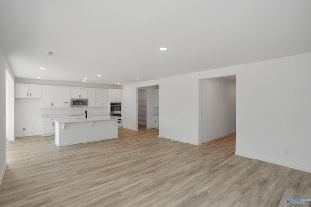 unfurnished living room with sink and light hardwood / wood-style floors