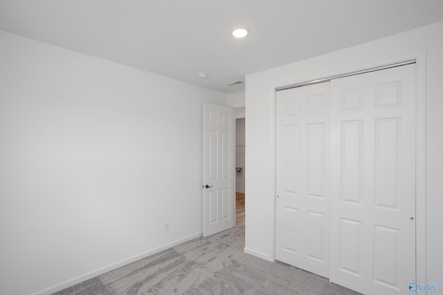 unfurnished bedroom with light carpet and a closet