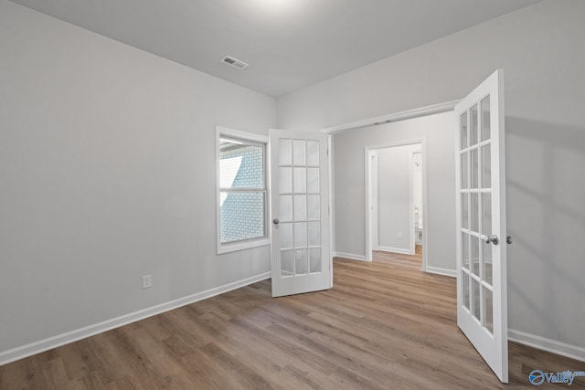 unfurnished room with french doors and light hardwood / wood-style flooring