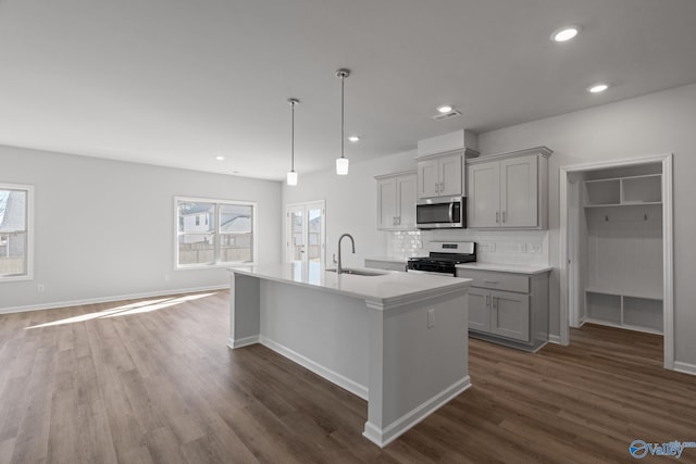 kitchen with hanging light fixtures, sink, backsplash, gray cabinetry, and stainless steel appliances