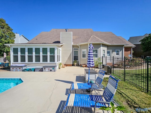 rear view of house with a swimming pool with hot tub, a yard, and a patio area