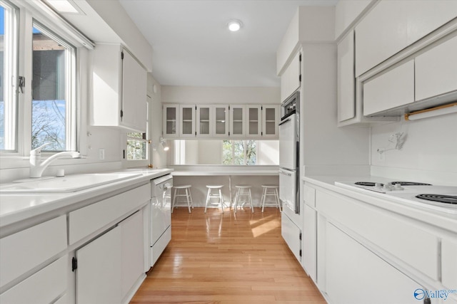 kitchen with white cabinetry, white appliances, sink, and light wood-type flooring