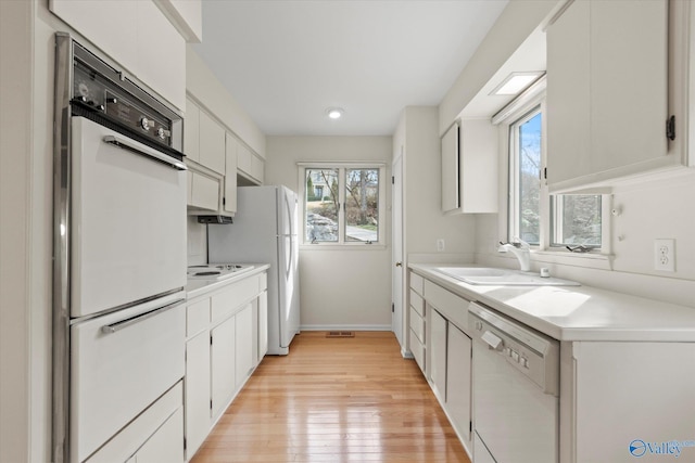 kitchen featuring white cabinetry, sink, white dishwasher, and a wealth of natural light