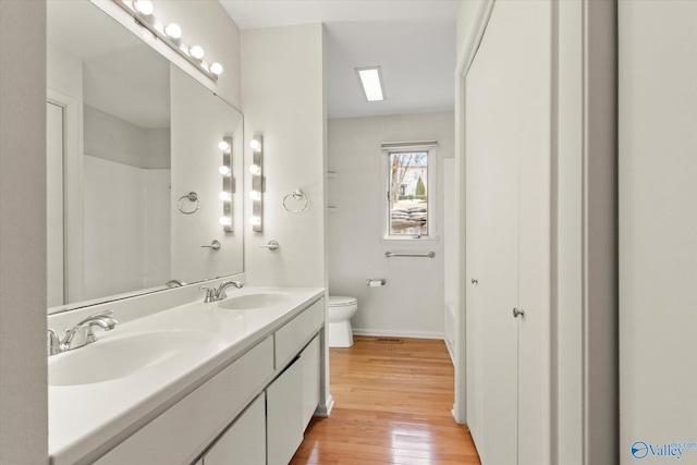 bathroom featuring wood-type flooring, toilet, and vanity