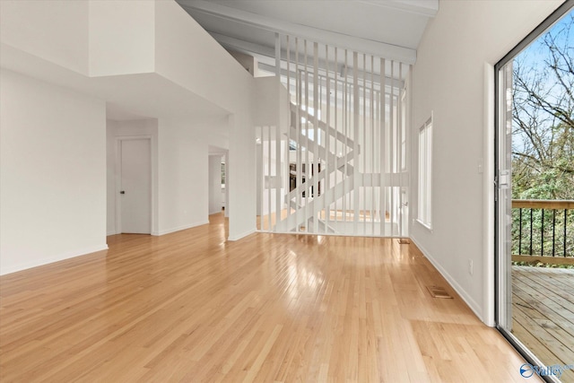 unfurnished living room with light hardwood / wood-style floors and a high ceiling