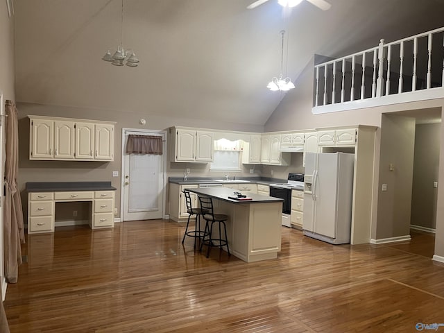 kitchen with high vaulted ceiling, hanging light fixtures, white refrigerator with ice dispenser, and range with electric cooktop