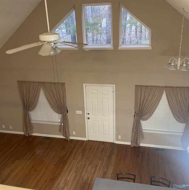 interior space featuring a healthy amount of sunlight, ceiling fan with notable chandelier, high vaulted ceiling, and dark hardwood / wood-style flooring