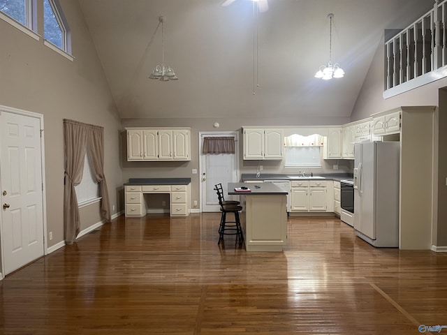 kitchen featuring white appliances, a kitchen island, white cabinetry, high vaulted ceiling, and a breakfast bar area