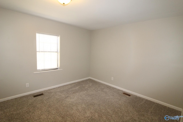 spare room featuring carpet floors, baseboards, and visible vents
