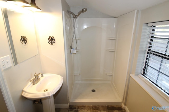 full bathroom featuring a sink, lofted ceiling, and a stall shower