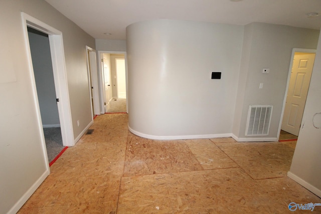 hallway featuring baseboards and visible vents