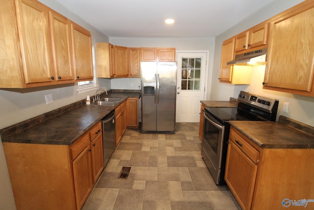 kitchen featuring under cabinet range hood, dark countertops, appliances with stainless steel finishes, and a sink