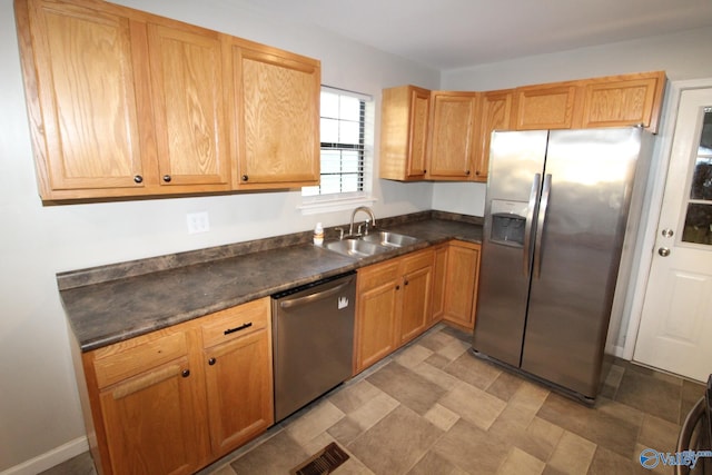 kitchen with a sink, appliances with stainless steel finishes, dark countertops, and visible vents
