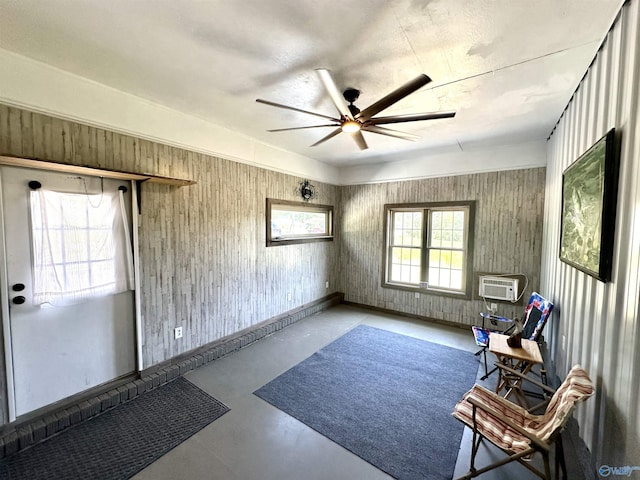 living area with a ceiling fan, finished concrete flooring, and baseboards