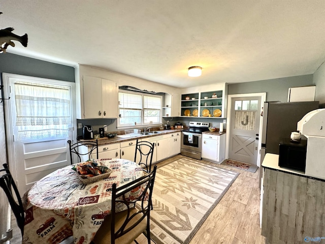 kitchen featuring electric range, dark countertops, light wood-type flooring, open shelves, and a sink