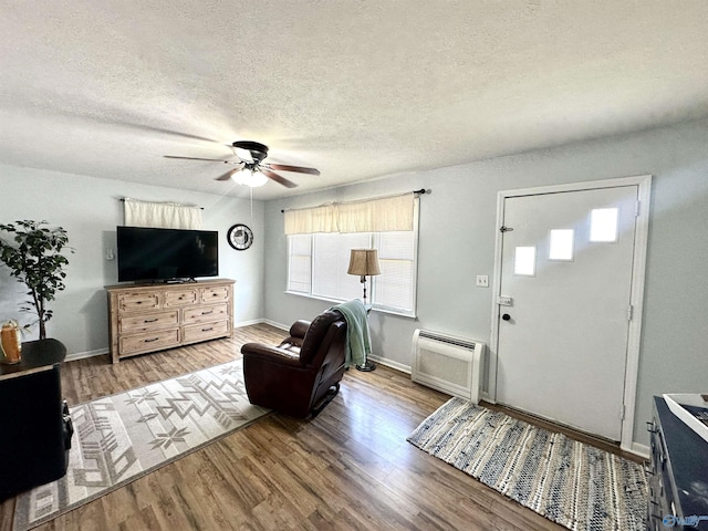 living room featuring a textured ceiling, ceiling fan, wood finished floors, and baseboards