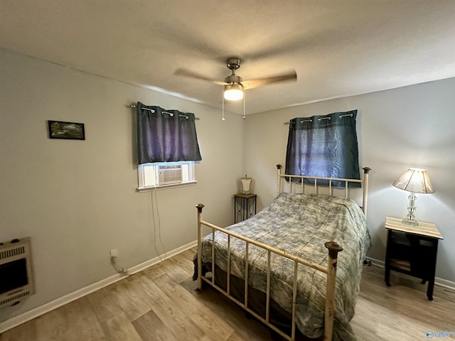 bedroom featuring heating unit, ceiling fan, wood finished floors, cooling unit, and baseboards