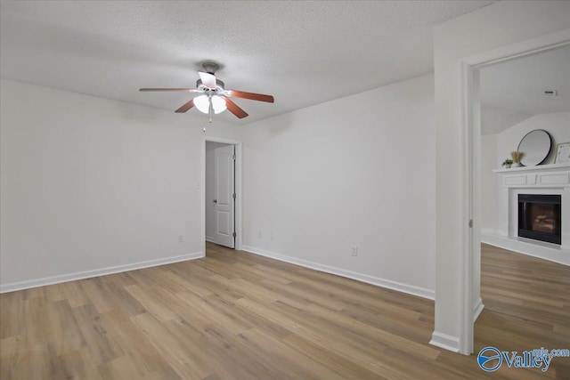 215 Shadow Ct SW, Huntsville, AL 35824 - empty room featuring wood finished floors, ceiling fan, a glass covered fireplace, and a textured ceiling