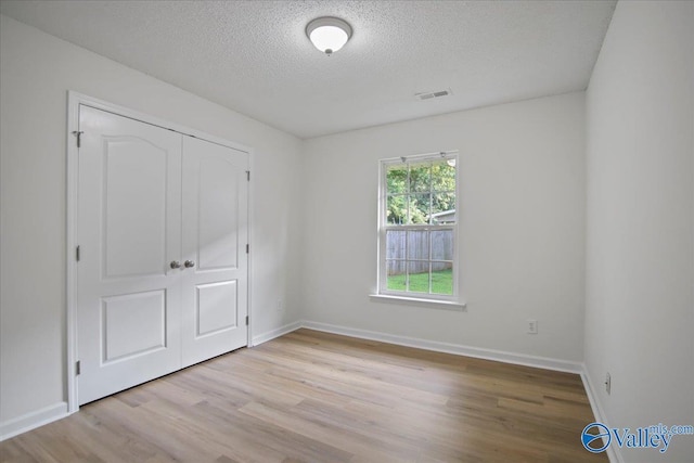 215 Shadow Ct SW, Huntsville, AL 35824 - unfurnished bedroom featuring a textured ceiling, light wood-style flooring, and a closet