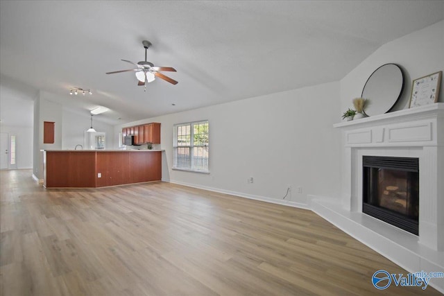 215 Shadow Ct SW, Huntsville, AL 35824 - unfurnished living room featuring vaulted ceiling, light wood-style floors, a fireplace with raised hearth, and a ceiling fan