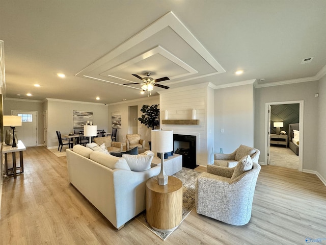 living room with crown molding, ceiling fan, a fireplace, and light hardwood / wood-style floors