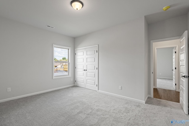 unfurnished bedroom with light carpet and a closet