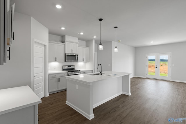 kitchen featuring appliances with stainless steel finishes, pendant lighting, white cabinetry, sink, and a kitchen island with sink