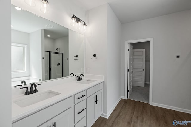 bathroom with wood-type flooring, a shower with shower door, and vanity