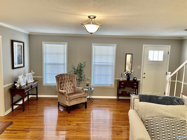 sitting room featuring hardwood / wood-style flooring, crown molding, and a textured ceiling