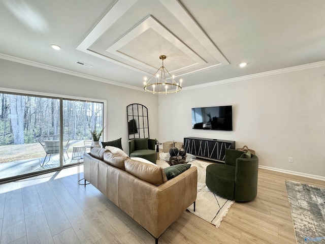 living area with ornamental molding, baseboards, a chandelier, a raised ceiling, and light wood-style floors
