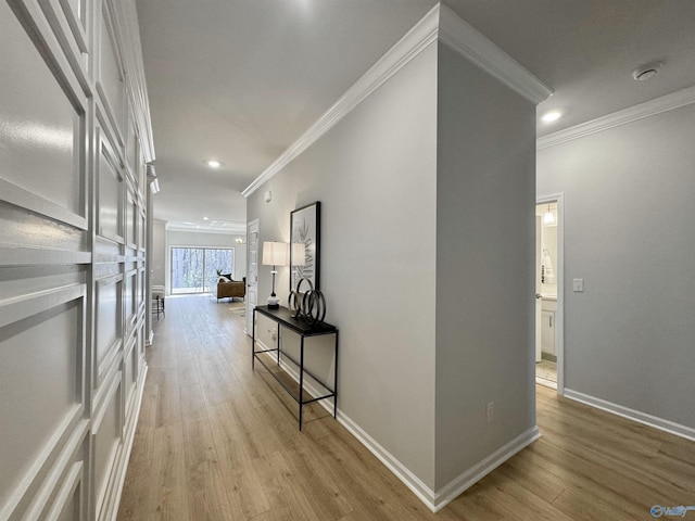hall featuring crown molding, baseboards, light wood finished floors, and recessed lighting