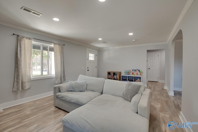 living area featuring arched walkways, visible vents, crown molding, and light wood-style floors