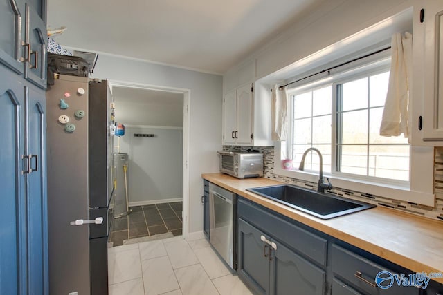 kitchen featuring stainless steel appliances, a sink, crown molding, tasteful backsplash, and butcher block counters