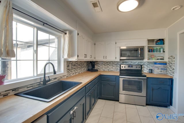 kitchen with visible vents, a sink, stainless steel appliances, butcher block counters, and decorative backsplash