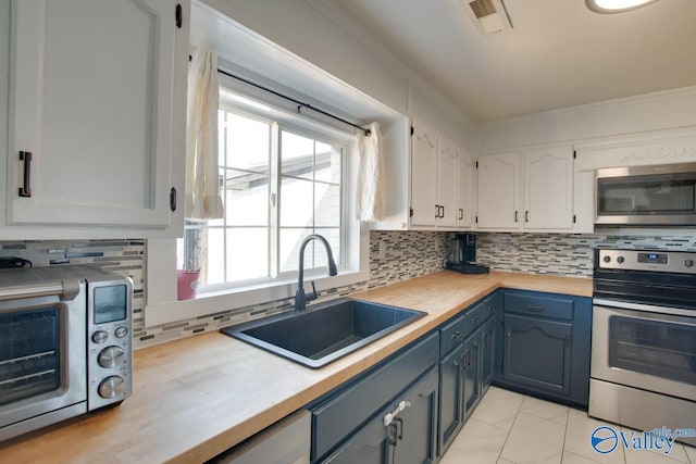 kitchen with visible vents, a sink, stainless steel appliances, white cabinets, and crown molding