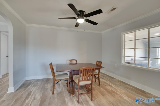 dining space with arched walkways, visible vents, crown molding, and light wood-style floors