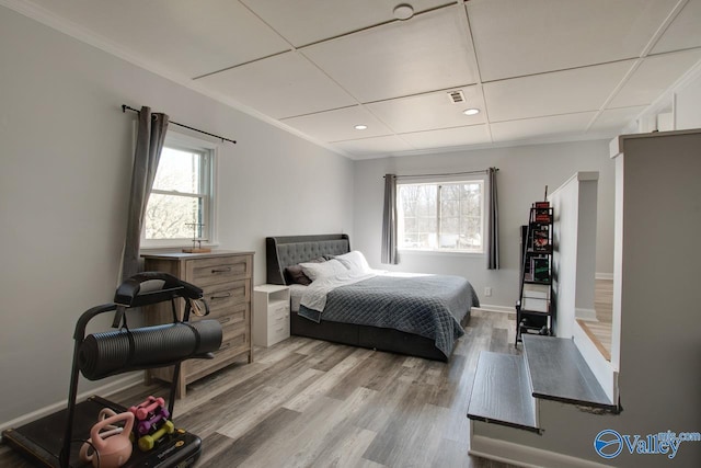 bedroom featuring multiple windows, visible vents, light wood finished floors, and ornamental molding