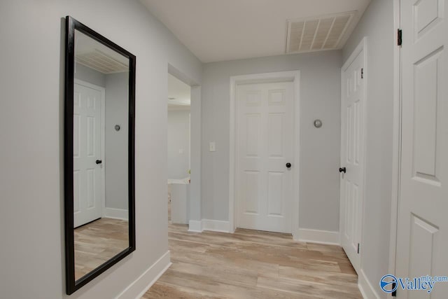 corridor featuring visible vents, light wood-style flooring, and baseboards